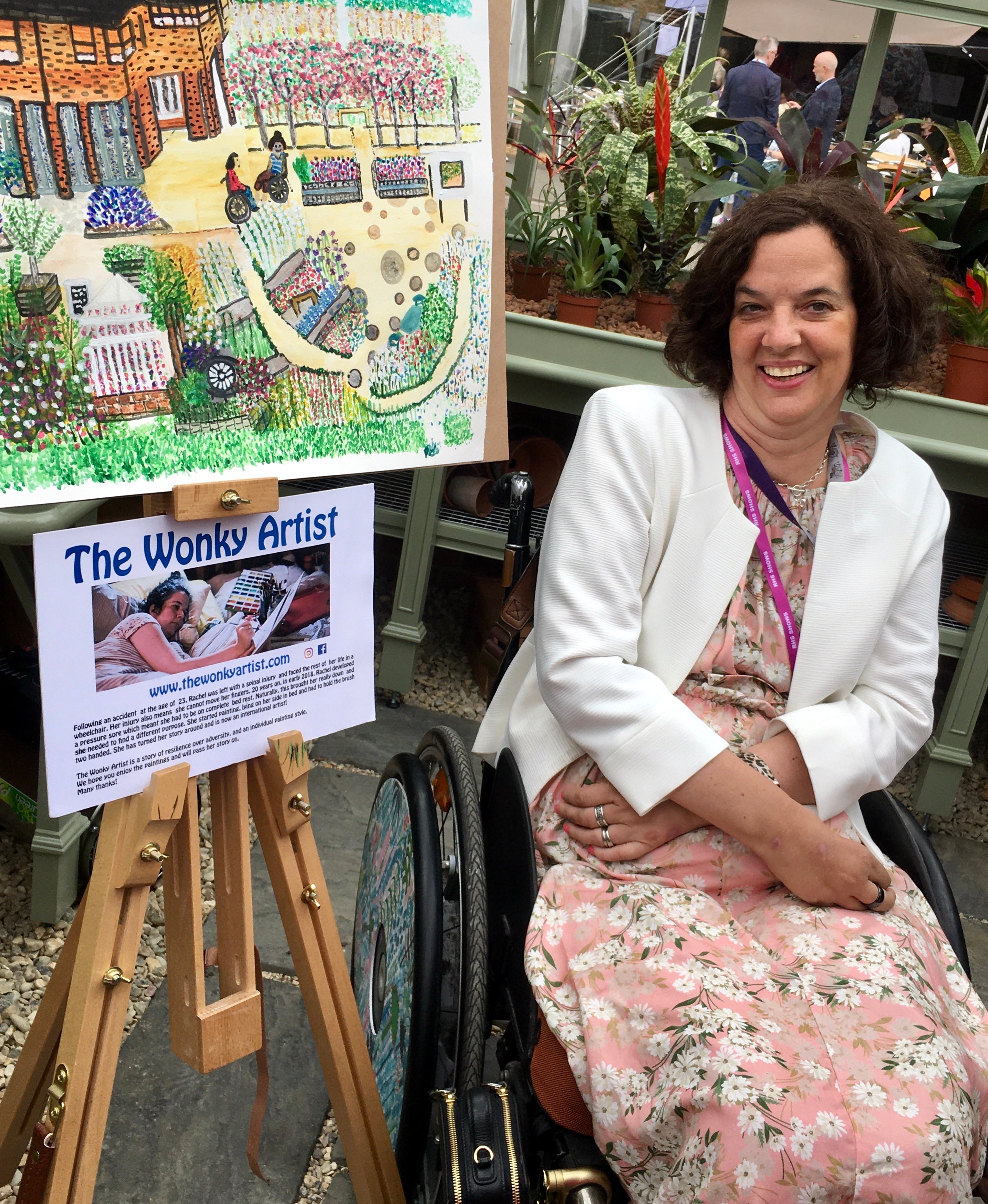 Woman in a wheelchair next to a large illustration of a garden scene, with 'The Wonky Artist' branding visible.